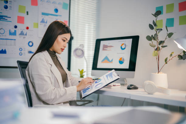 istock Professional businesswoman analyzing financial reports, developing strategic marketing plan, working intently at modern office workspace with laptop and paperwork 2195417343