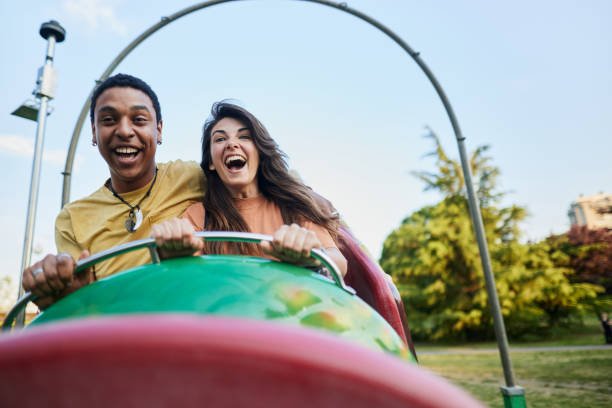 istock Happy couple having fun while riding on rollercoaster at amusement park. 2195420326