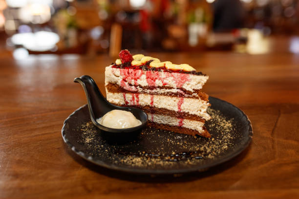 Delicious Slice of Layered Cake with Ice Cream on a Black Plate