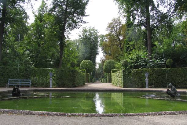 istock Garden view with pond and statues under clear sky. 2195421641