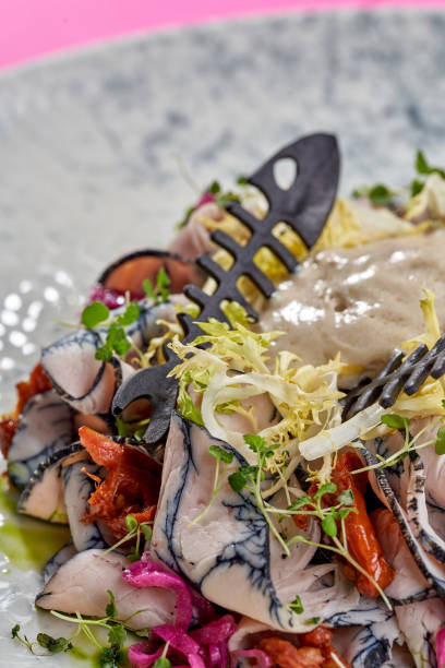 istock A gourmet salad featuring thinly sliced prosciutto, arugula, and a creamy anchovy dressing. The dish is garnished with crispy croutons and a drizzle of balsamic glaze 2195422031