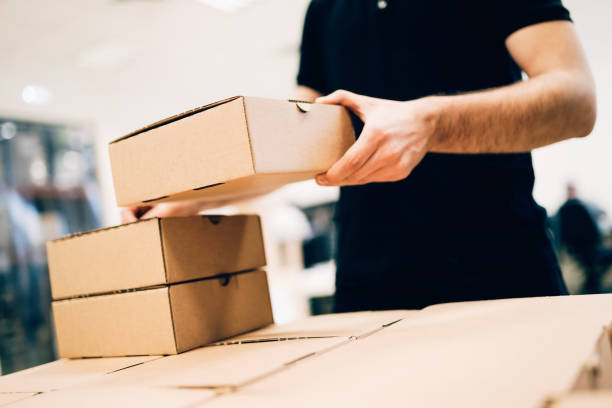 istock Young delivery man holding and carrying card box 2195423822