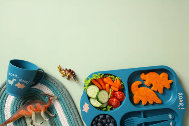 istock Dinosaur-themed kids meal set on green background. Flat lay, top view 2195423882