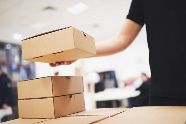 istock Young delivery man holding and carrying card box 2195423956