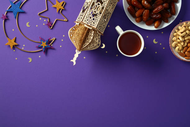 istock Ramadan celebration background with traditional lantern, dates, nuts, tea, and festive decorations on a purple backdrop 2195425463