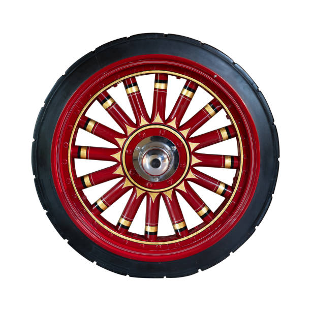 A vintage wagon wheel with red and black spokes featuring intricate decorative details and shiny hubcap