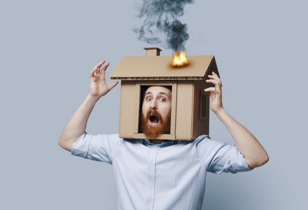 istock Homeowner with his head inside a burning cardboard house 2195427702