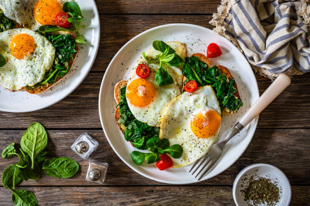 istock Crispy toast with stewed spinach and fried eggs with runny yolks on wooden table 2195428292