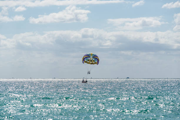 Colorful parasail wing pulled by a boat in the sea water Miami, FL, USA - March 30, 2024: Parasailing over the Atlantic Ocean in Miami Beach, Florida, USA. miami parachuting stock pictures, royalty-free photos & images