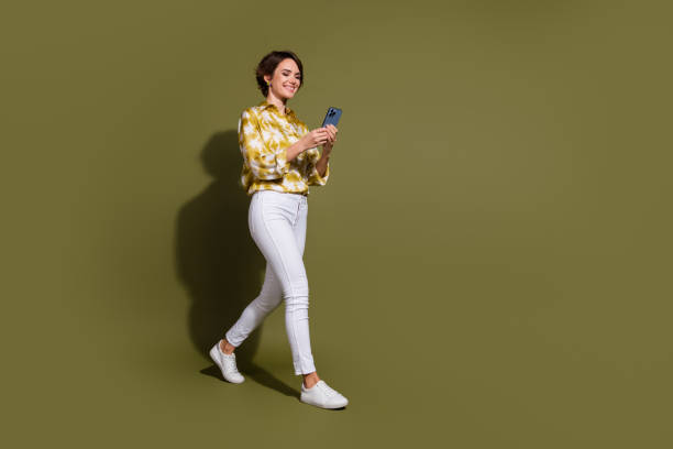 istock Confident young woman using smartphone in stylish apparel on khaki background 2195432890
