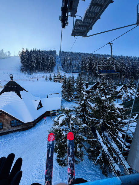 istock Skiers riding a cable lift over snowy slopes under a clear blue sky 2195436254