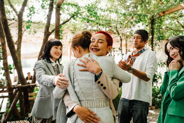 A heartfelt hug shared at a Thai wedding, capturing joyful connections, cultural traditions, and vibrant community bonds in a serene outdoor setting.