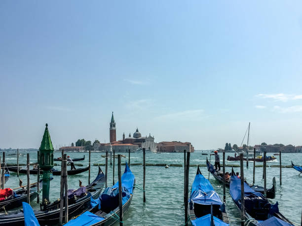 This photo captures a picturesque scene in Venice. A fleet of gondolas is moored in the water, with the iconic silhouette of San Giorgio Maggiore and its bell tower visible in the distance. The image evokes a sense of tranquility and showcases the beauty of this iconic Venetian landmark.