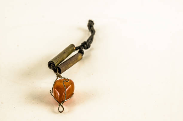 A necklace with a stone and a metal piece. The stone is orange and the metal piece is brown