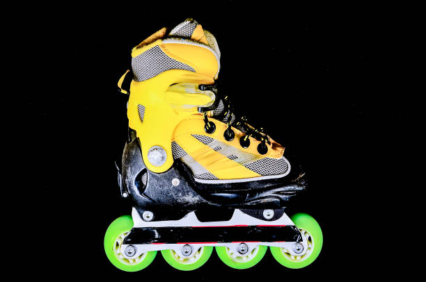A yellow and black roller skate with green wheels. The skate is ready to be used