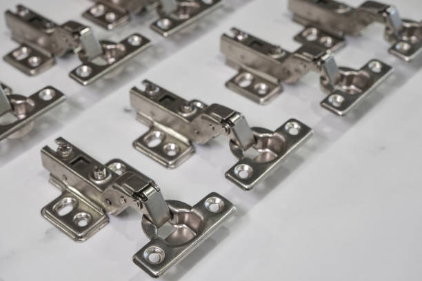 istock Close-up of metal cabinet hinges arranged on a white surface. 2195442094