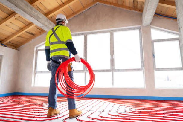 Worker Installing Underfloor Heating System with Red Pipes in New Building