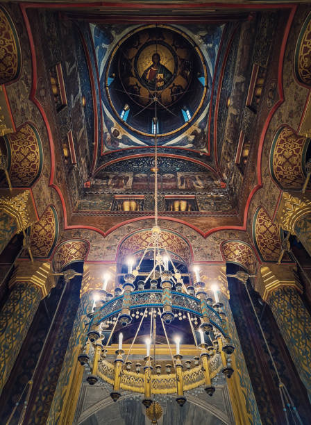 istock Interior architectural details of the Curtea de Arges monastery. The hall with tall columns, christian Orthodox painted icons on walls and a golden chandelier with lights suspend out of ceiling 2195446909