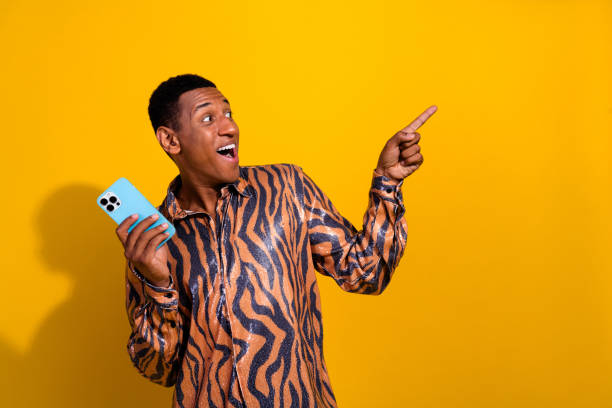 istock Young man with an excited expression holding a smartphone against a vibrant yellow background 2195447797