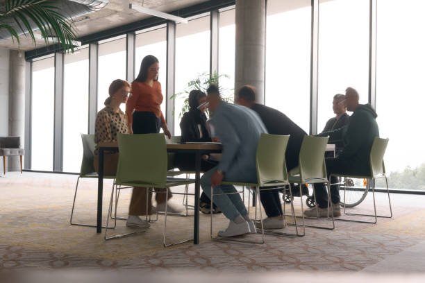 istock A diverse business team, working urgently around a conference table, collaborates on a meeting while their director, seated in a wheelchair, waits for their input 2195447896