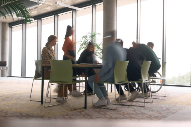 istock A diverse business team, working urgently around a conference table, collaborates on a meeting while their director, seated in a wheelchair, waits for their input 2195449371