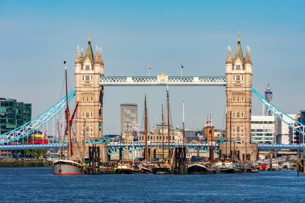 Southbank Boardwalk, London, England, United Kingdom, Europe - November 2nd 2025:  A small group of barges anchored in the River Thames surrounded by autumn-colored trees, with cranes towering above a city construction site in the background.