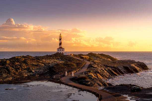 istock Tranquil Coastal Morning, Faro de Favaritx, Menorca. Lighthouse glowing under soft dawn light with vibrant skies and a peaceful seascape 2195449713