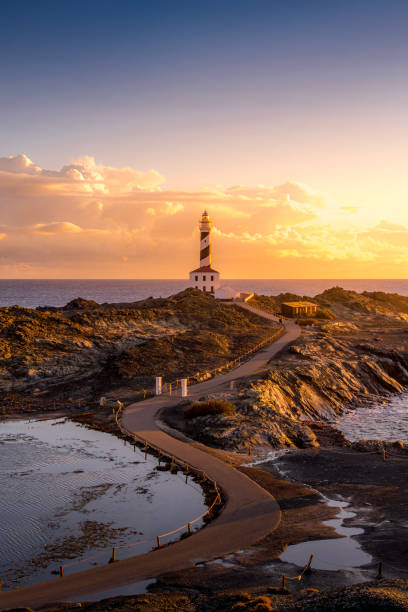 istock Tranquil Coastal Morning, Faro de Favaritx, Menorca. Lighthouse glowing under soft dawn light with vibrant skies and a peaceful seascape 2195449724