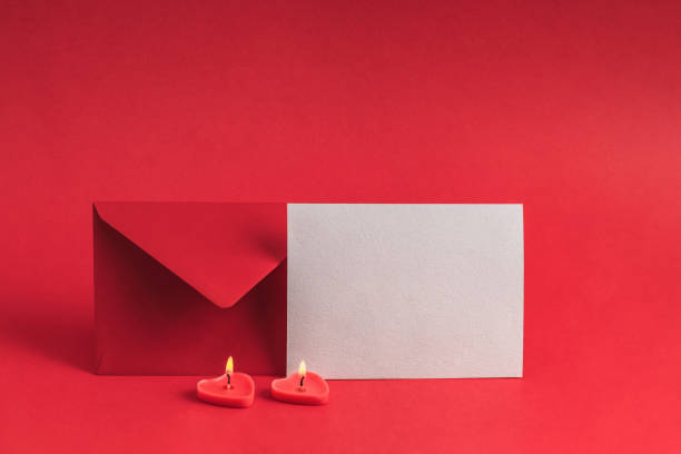 istock Lit miniature heart-shaped candles, red envelope and empty blank on red background. Valentine's Day and birthday greeting card mockup. 2195451208
