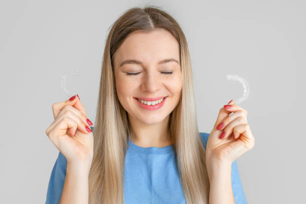 istock Caucasian woman with white smile holding transparent removable retainer. Bite correction device. 2195452514