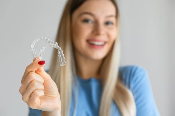 istock Caucasian woman with white smile holding transparent removable retainer. Bite correction device. 2195452530