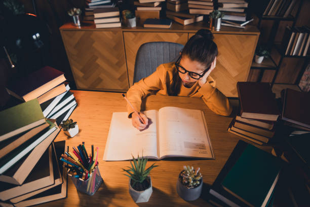 istock Young girl studying in a cozy home environment surrounded by books 2195454704