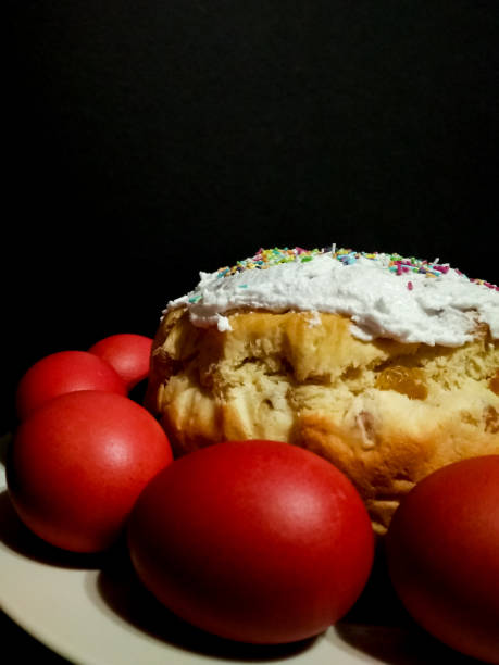istock Easter cake bread Kulich featuring red eggs, white icing, colorful sprinkles, symbolizing springtime celebration on rustic wooden background. Vertical mobile photo 2195454824