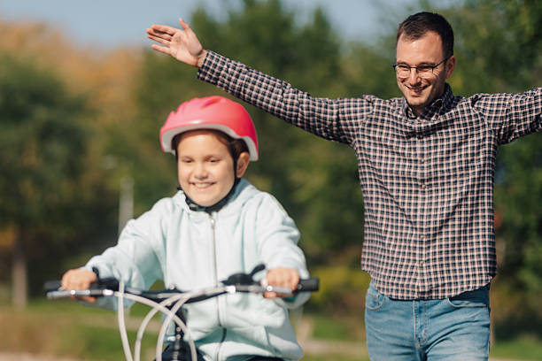 istock Father teaching daughter riding bicycle in park during summer day 2195458446