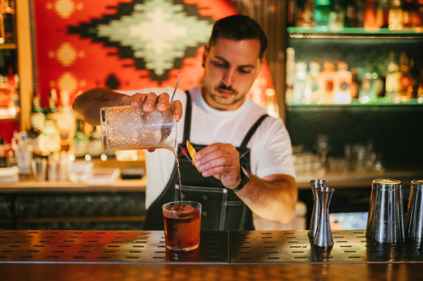 istock Male bartender preparing Negroni cocktail with an orange zest. 2195460979