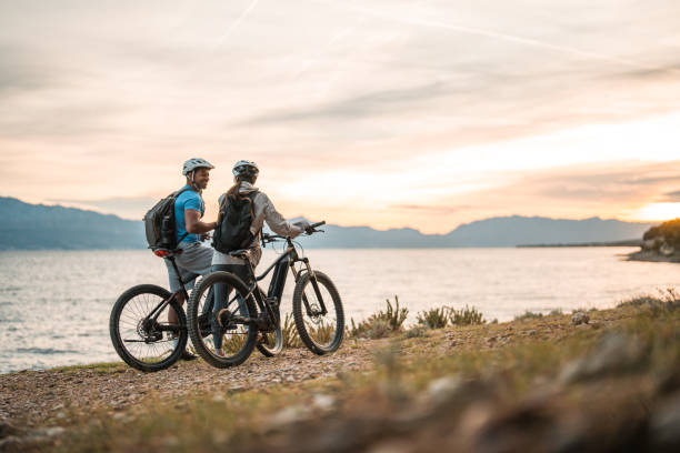 istock Diverse Couple with E-Bikes Relishing Seaside Sunrise 2195462113