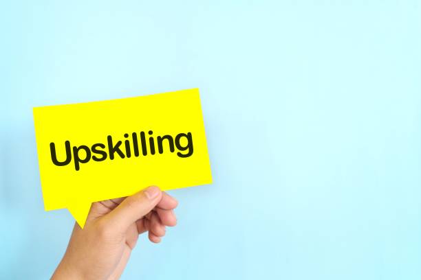istock Human hand holding yellow speech bubble with written phrase Upskilling. Upskilling in workplace. 2195462221