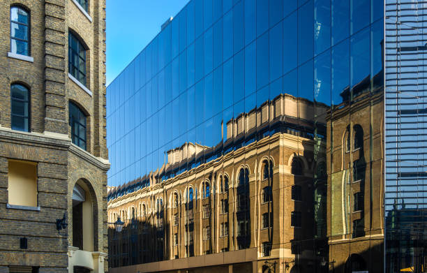 A modern glass building reflecting the historic architecture of an older brick structure. The contrast between the sleek glass and the textured brick creates an interesting visual dynamic.