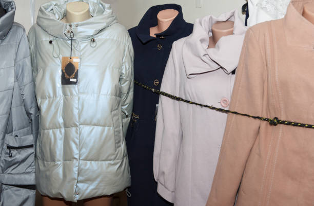 A variety of beauty winter coats, including beige, blue, and white, displayed on mannequins in a shop interior, showcasing fashion styles