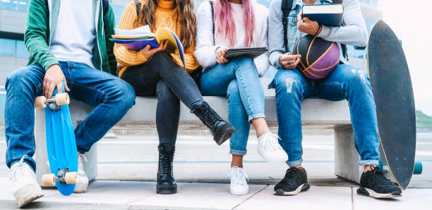 istock Group of students with digital tablet and books study together outdoors - Multiethnic young friends sitting on bench near university building  schoolwork after sport 2195469852