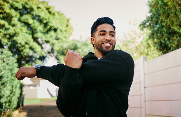 istock Smiling Man Stretching Arms During Warmup in Park 2195471618
