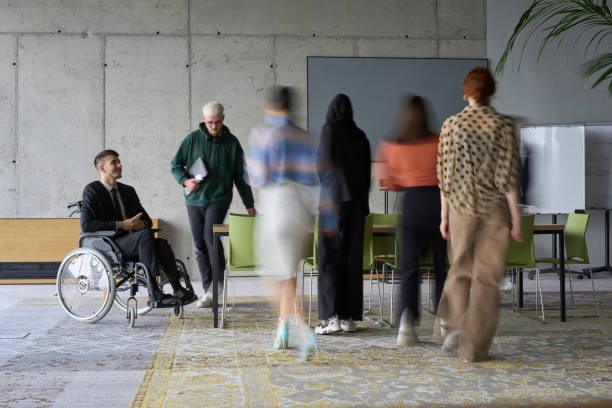 istock A diverse business team, working urgently around a conference table, collaborates on a meeting while their director, seated in a wheelchair, waits for their input 2195473957