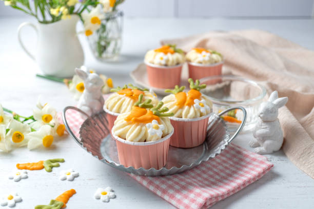 Carrot cake cupcakes for Easter. Carrot cupcakes with cream cheese frosting decorated with little chocolate carrots on white background.
