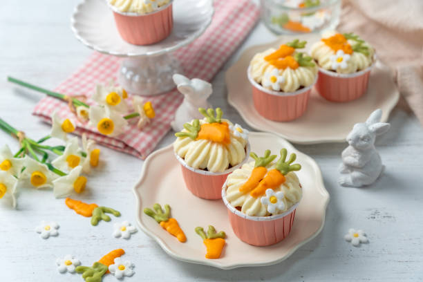 Carrot cake cupcakes for Easter. Carrot cupcakes with cream cheese frosting decorated with little chocolate carrots on white background.