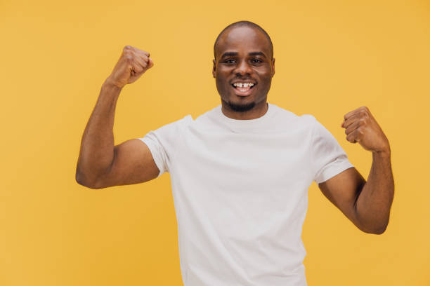 istock Strong African American man flexing biceps on yellow background 2195477916