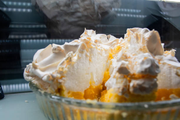 A glass bowl filled with a dessert with Lemon Meringue Pie. The dessert is cut in sections, revealing a yellow and white filling