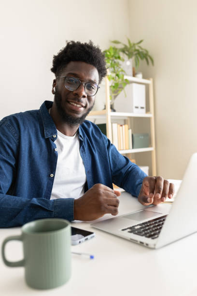 istock Young black businessman working from home using laptop and smiling at camera 2195478419