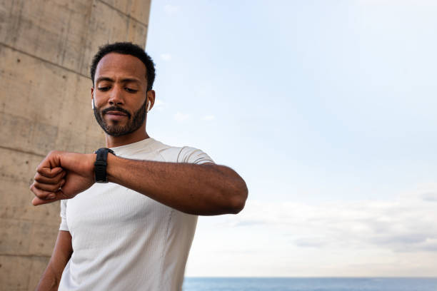 istock Young sportsman checking performance on smartwatch during training by the sea 2195478447
