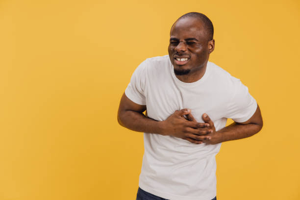 istock Young man clutching his chest experiencing sudden heart attack on yellow background 2195478459