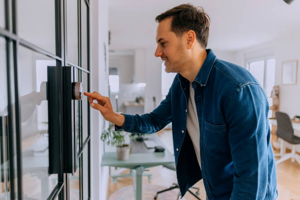 istock Young casually clothed man adjusts the temperature at home with a device on the wall 2195480942